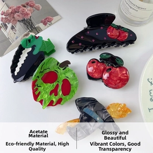Detail of unique acetate hair clips with red apple and green skull apple designs