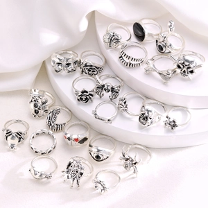 Close-up of 24pcs punk rings set featuring skull, spider, and evil eye on white velvet