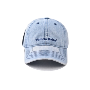 Détail de la broderie de petites lettres sur casquette en denim délavé au style vintage