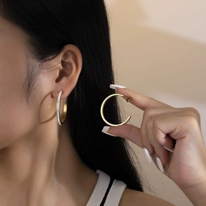 Close-up of elegant C-shaped gold hoop earrings with sparkling rhinestones on model