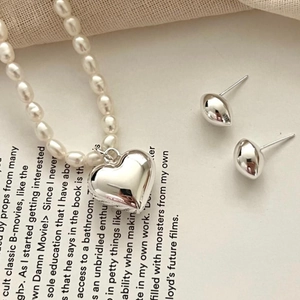 Detail of silver heart pendant on pearl necklace and matching earrings on a magazine
