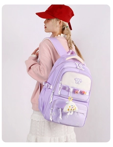 Side view of a purple school backpack with white pockets and cute accessories on a model