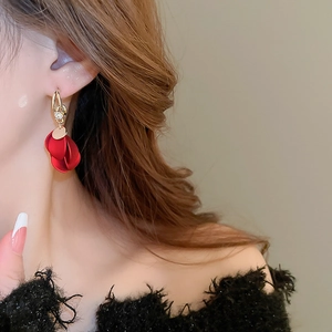 Close-up of red matte petal tassel earrings with a gold metal clasp on a model