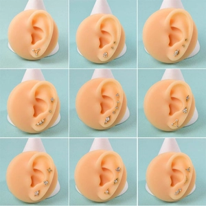 Macro detail of nine gold stainless steel piercing sets on silicone ear models