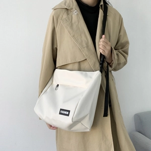 Detailed look at off-white canvas messenger bag with adjustable strap on a model