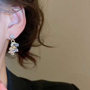 Detail of gold horse earring with colorful crystals on model with soft lighting