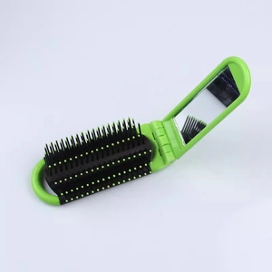Detail view of compact green folding hairbrush with integrated mirror and massage bristles