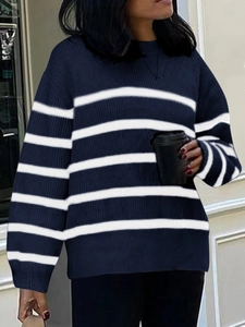 Detail of loose fit navy blue and white striped knitted sweater in an urban street setting