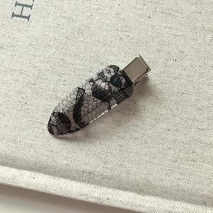 Lace print hair clip with elegant black pattern on a textured fabric background