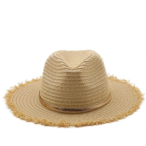 Detail of raffia sun hat featuring a gold metallic band and stylish frayed tassel edges