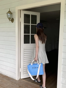 Blue woven tote bag with white shoulder straps and PARIS print shown on female model