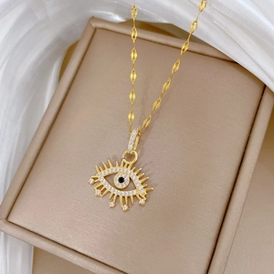 Macro view of gold devil eye pendant with clear and black crystals on a necklace