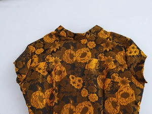 Close-up of vintage brown and gold floral jacquard fabric with a mandarin collar