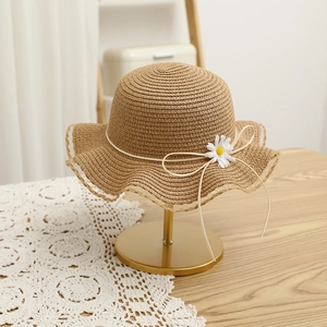 Close-up of a khaki straw sun hat with wavy brim and a delicate white daisy flower