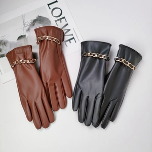 Detail of brown and black PU leather gloves featuring decorative gold metal wrist chains