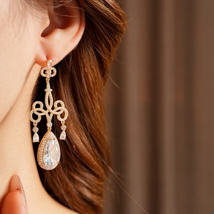 Gros plan de boucles d'oreilles gouttes dorées avec cristaux portées par un mannequin