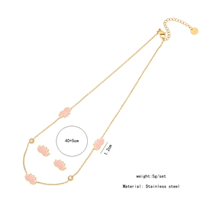 Detail showing pink lotus necklace and earring set in gold stainless steel finish