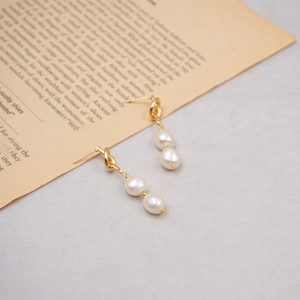 French vintage gold knot earrings with elegant double freshwater pearls on book background