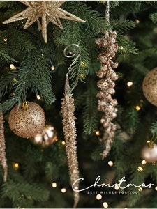 Close-up of gold Christmas tree ornaments with sequins and warm LED lights