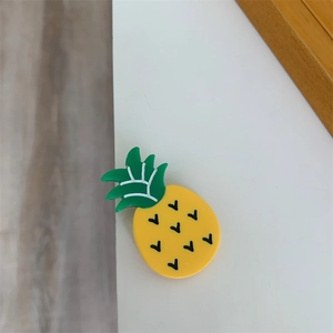 Close-up of a small yellow pineapple-shaped hair clip made of glossy acetate resin