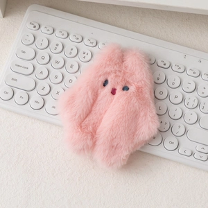 Gros plan d'un porte-monnaie lapin en peluche rose avec yeux bleus sur un clavier