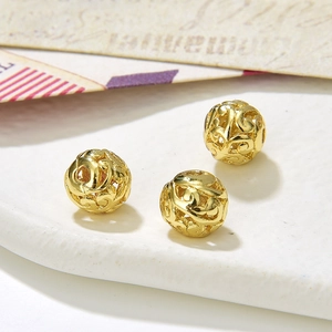 Detailed macro view of three vintage gold hollow round alloy beads with floral patterns