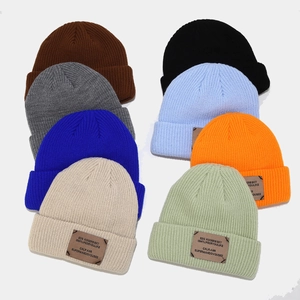 Flat lay of colorful ribbed knit beanies showing various shades and leather patch detail