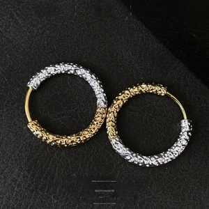 Detail view of gold and silver contrast hoop earrings with unique lava texture on leather