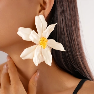 Close-up of a white acrylic flower earring with yellow beads on a model side profile