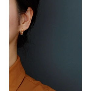 Close-up of elegant gold plated 925 silver hoop earring with zircon inlay on model ear