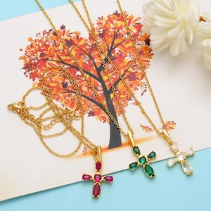 Detailed view of the gold cross necklace with pear-cut gemstones and sparkling rhinestones