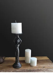 Detail of vintage iron angel candle holders with white candles on a rustic wooden table