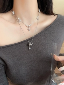 Detail of layered pearl necklace with star and Saturn pendant and teardrop crystal