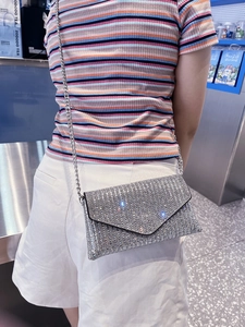 Detailed side view of a sparkling rhinestone envelope bag with a fine silver chain strap