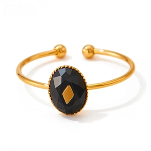 Macro detail of gold open bangle featuring a black oval gemstone with diamond-shaped inlay