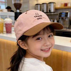 Close-up of pink and brown kids' baseball cap with embroidered smile face and text