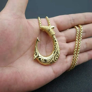Gold Viking fish hook pendant necklace with twisted rope chain held in hand for display