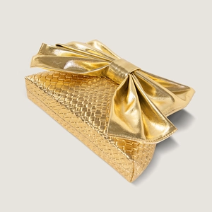Detailed view of the woven metallic gold texture and oversized bow on the clutch bag