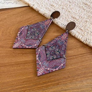 Detailed macro view of geometric wooden diamond earrings with ethnic bohemian patterns
