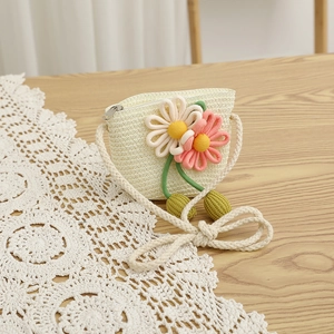 Detail of children's handmade woven straw bag with floral accents on a wooden background
