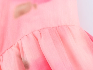 Vista macro del tessuto in chiffon tie-dye rosa con pieghe e cuciture di precisione