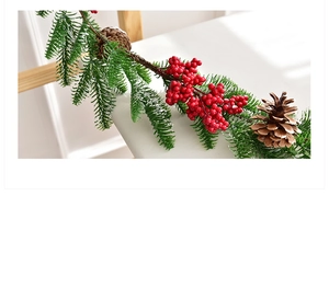 Detail of Christmas wreath featuring green pine needles, red berries and natural pinecones