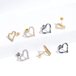 Macro detail of heart-shaped earrings with colorful zircons on textured stone