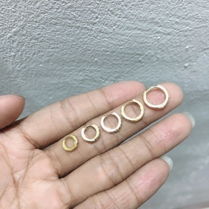 Five sizes of gold hoop earrings with white zircon accents displayed on fingers