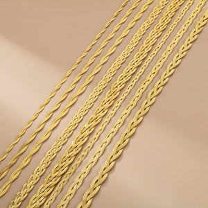 Macro shot of gold braided snake chain necklaces with metallic texture on pink background