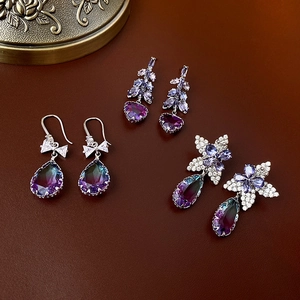 Détail de boucles d'oreilles en argent avec cristaux violets et diamants sur fond marron