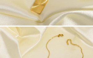 Dettaglio del ciondolo rettangolare a moneta solare placcato oro 18K su seta beige