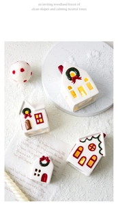 Macro view of white ceramic LED Christmas houses with green wreaths and red chimney details