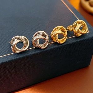 Vue détaillée des boucles d'oreilles torsadées dorées et argentées sur boîte à bijoux