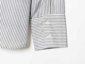 Détail du poignet d'une chemise en popeline avec rayures grises et boutons blancs